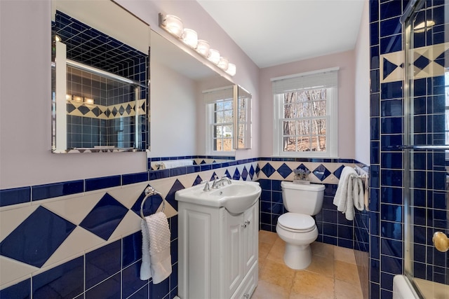 full bath with a wainscoted wall, tile walls, toilet, a tile shower, and vanity