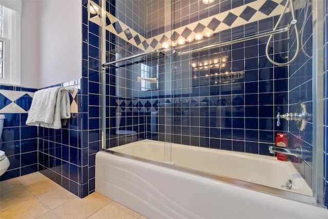 bathroom with toilet, shower / bath combination with glass door, tile walls, and tile patterned floors