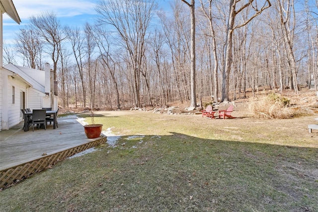 view of yard with a wooded view and a wooden deck