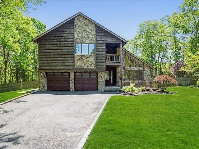 view of front of property with a balcony, stone siding, driveway, and a front yard