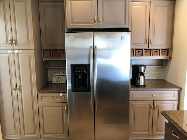 kitchen featuring dark stone counters, stainless steel refrigerator with ice dispenser, and backsplash