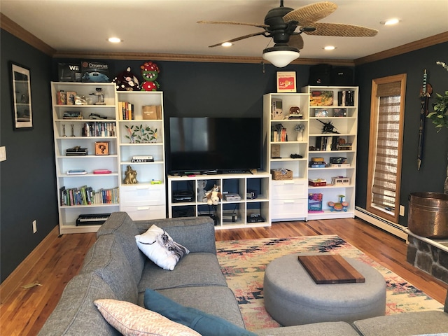 living area with ceiling fan, a baseboard heating unit, ornamental molding, and wood finished floors