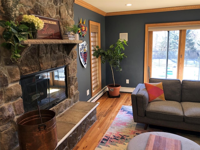 living room featuring wood finished floors, baseboard heating, crown molding, and a stone fireplace