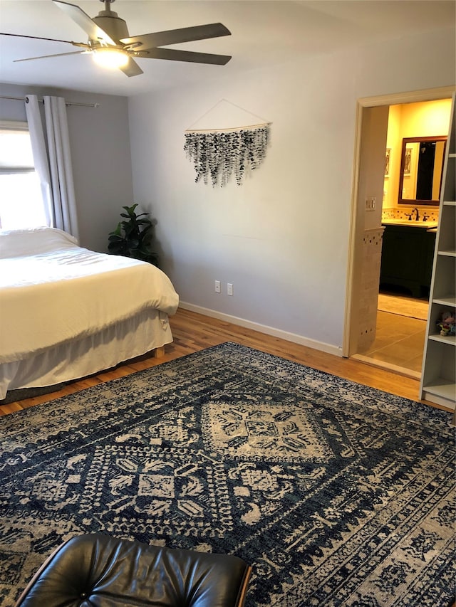 bedroom with a sink, ceiling fan, baseboards, and wood finished floors