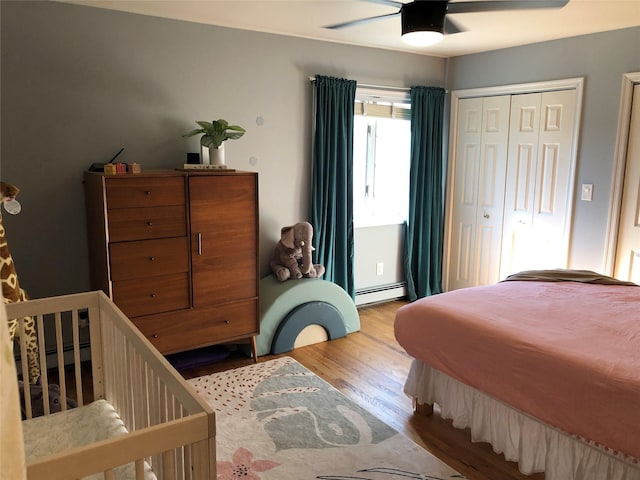 bedroom with a baseboard heating unit, ceiling fan, and wood finished floors