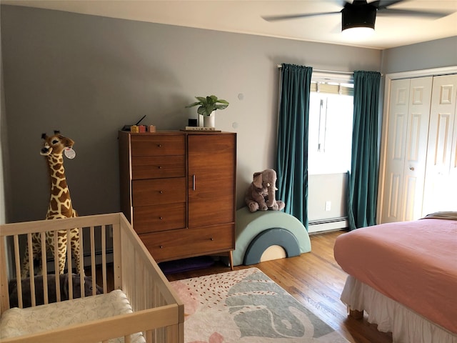 bedroom featuring ceiling fan, baseboard heating, and wood finished floors