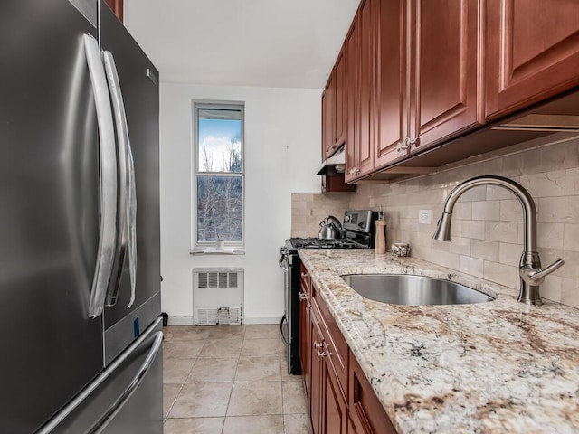 kitchen featuring stainless steel appliances, a sink, backsplash, and light stone counters