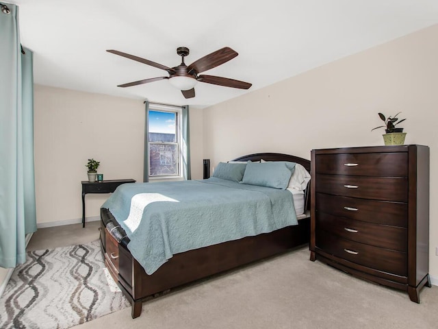 bedroom with light colored carpet, ceiling fan, and baseboards