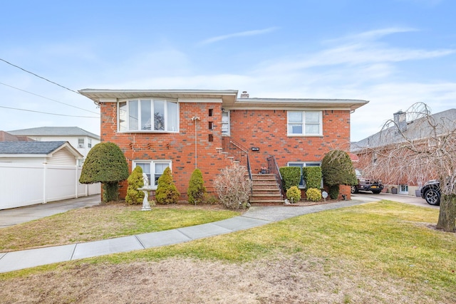 view of front of home featuring brick siding, fence, and a front lawn