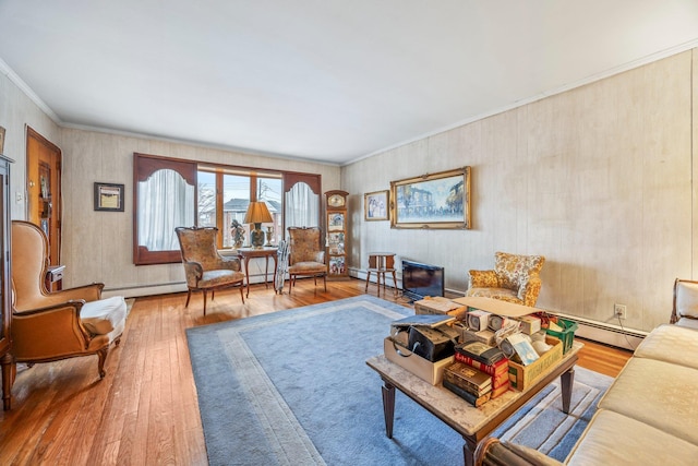 living room with a baseboard heating unit, hardwood / wood-style floors, and crown molding