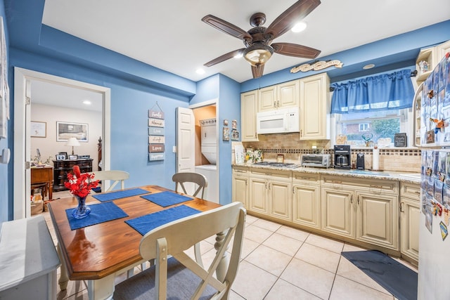 15744 97th St, Howard Beach, NY 11414 - kitchen featuring light tile patterned floors, white microwave, stacked washing maching and dryer, decorative backsplash, and stainless steel gas stovetop