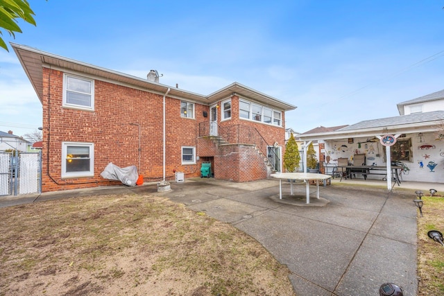 15744 97th St, Howard Beach, NY 11414 - rear view of property featuring brick siding, fence, a lawn, a gate, and a patio area