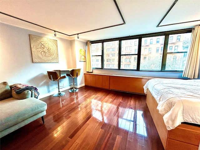 bedroom with rail lighting, baseboards, and wood-type flooring