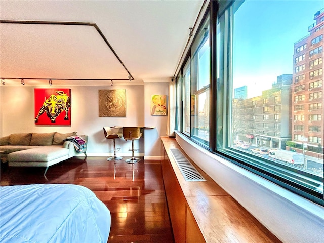 bedroom featuring visible vents, baseboards, wood finished floors, and a view of city