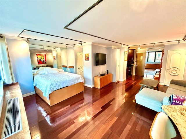 bedroom with track lighting, baseboards, and dark wood-style flooring