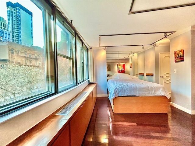 bedroom with track lighting, visible vents, baseboards, and wood finished floors