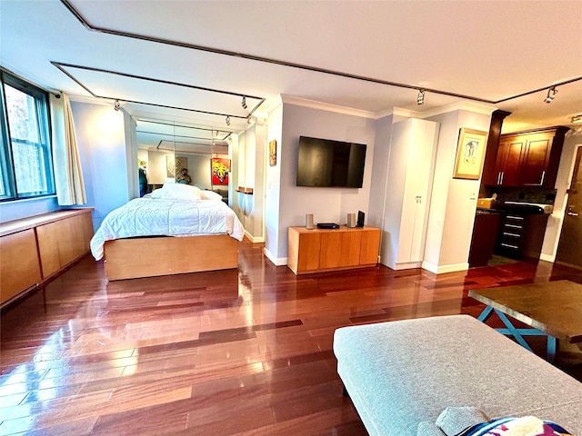 bedroom with crown molding, rail lighting, baseboards, and dark wood-style flooring