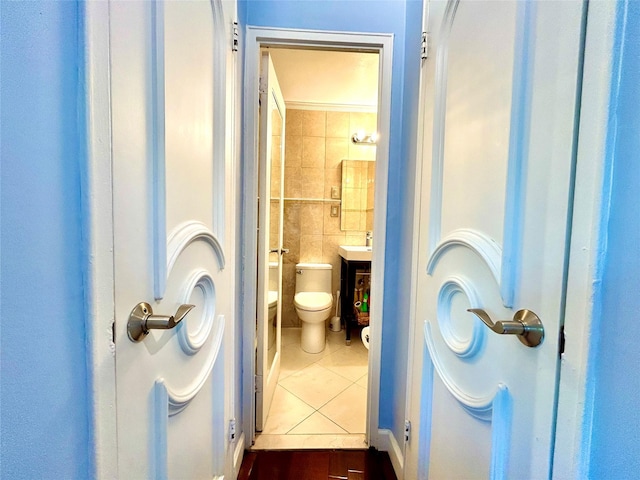 bathroom with toilet, tile walls, and tile patterned flooring