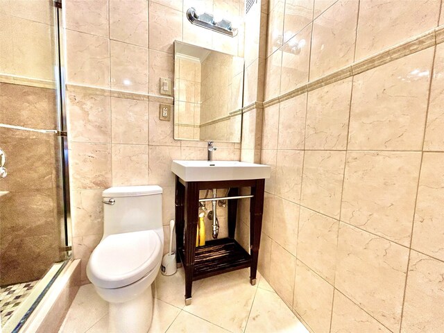 bathroom featuring toilet, vanity, a stall shower, tile patterned floors, and tile walls