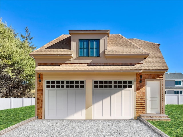 view of front of house featuring a garage, roof with shingles, fence, and gravel driveway