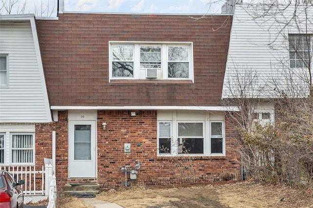 view of property with entry steps, mansard roof, roof with shingles, and brick siding