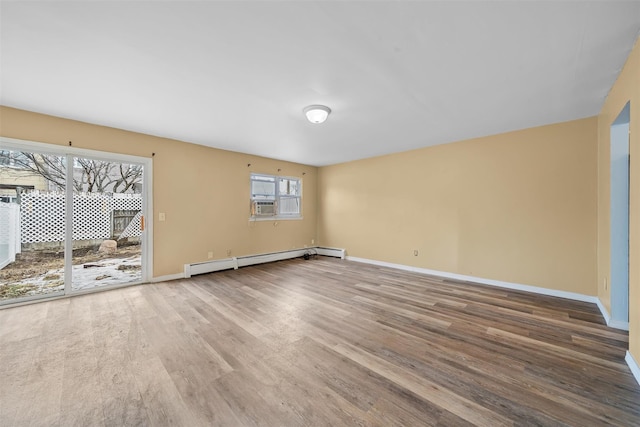 empty room with a baseboard radiator, baseboards, and wood finished floors