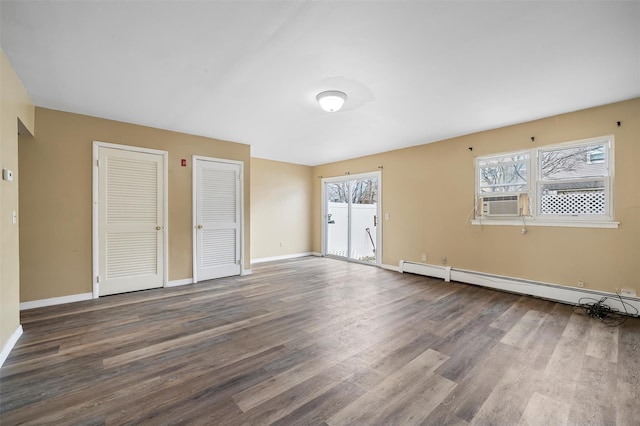 unfurnished bedroom featuring baseboards, a baseboard radiator, wood finished floors, and multiple closets