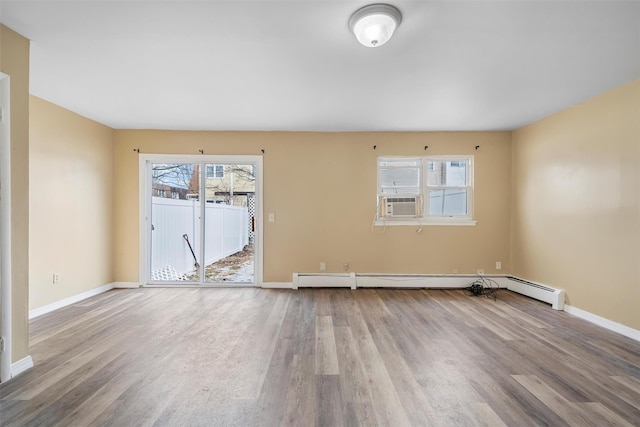 unfurnished room featuring a baseboard radiator, baseboards, and wood finished floors