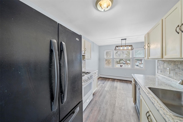 kitchen with a sink, light wood-style floors, backsplash, freestanding refrigerator, and white gas range