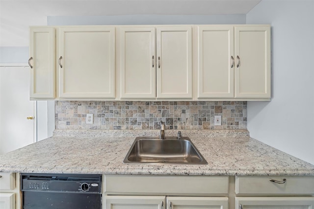 kitchen featuring light stone countertops, black dishwasher, backsplash, and a sink