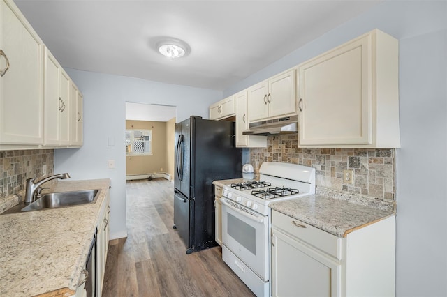 kitchen featuring under cabinet range hood, white range with gas stovetop, a sink, freestanding refrigerator, and dark wood-style floors