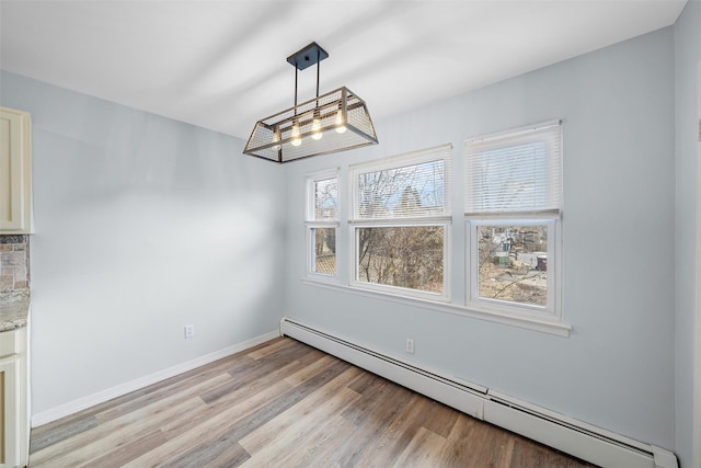 unfurnished dining area with light wood-style floors, a baseboard radiator, and baseboards