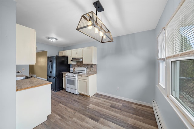 kitchen with tasteful backsplash, white gas range oven, baseboards, dark wood-type flooring, and freestanding refrigerator