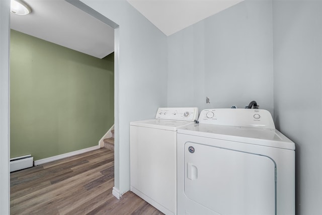 laundry area featuring laundry area, baseboards, a baseboard radiator, wood finished floors, and washer and dryer