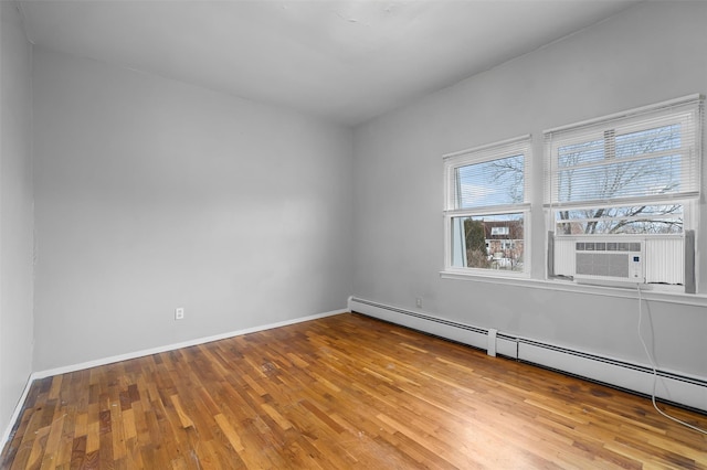 empty room with baseboard heating, cooling unit, wood finished floors, and baseboards