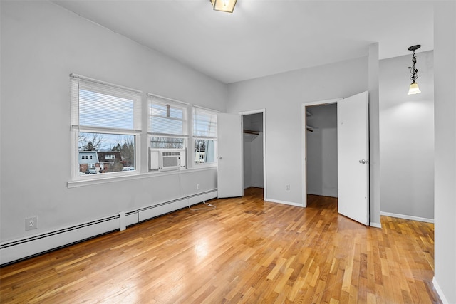 unfurnished bedroom with light wood finished floors, a baseboard radiator, and baseboards