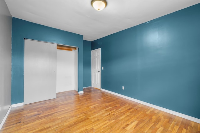 unfurnished bedroom featuring light wood-style floors, a closet, and baseboards