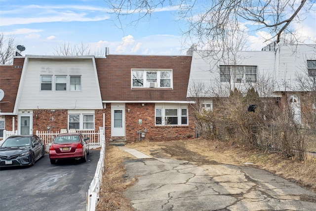 multi unit property featuring brick siding, roof with shingles, and mansard roof