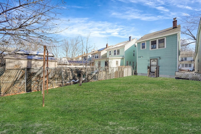 view of yard featuring entry steps, fence, and a residential view