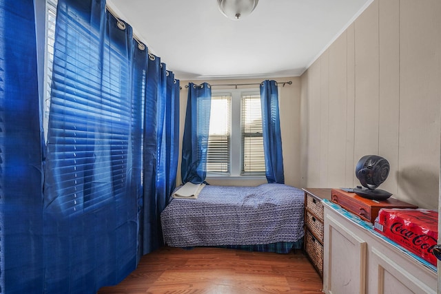 bedroom with ornamental molding and wood finished floors