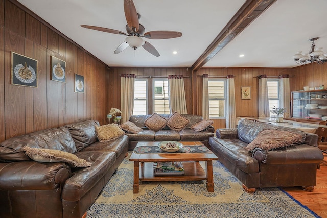 living room featuring ceiling fan with notable chandelier, recessed lighting, wood finished floors, and wooden walls