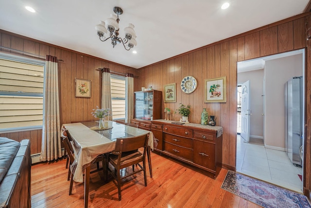 dining area featuring ornamental molding, light wood finished floors, an inviting chandelier, and baseboards