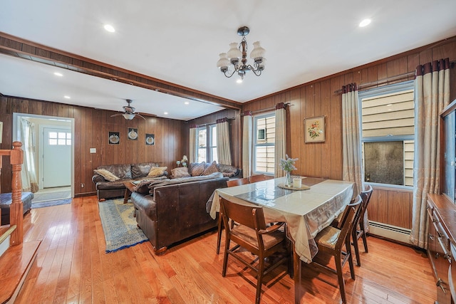 dining room with beamed ceiling, light wood-type flooring, a wealth of natural light, and wooden walls