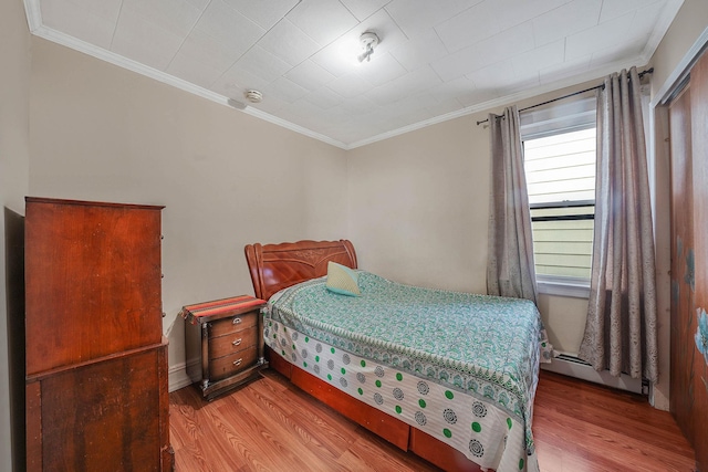 bedroom with light wood-type flooring, a baseboard radiator, and crown molding