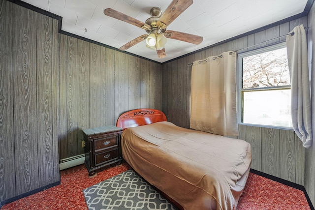 bedroom featuring a baseboard heating unit, carpet floors, wood walls, and ceiling fan