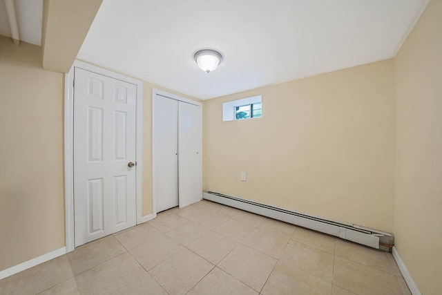 unfurnished bedroom with a baseboard radiator, a closet, light tile patterned flooring, and baseboards