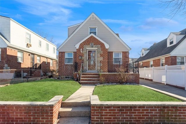 view of front of home featuring brick siding, fence, and a front lawn