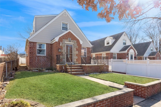 view of front facade with a fenced backyard, a front lawn, and brick siding