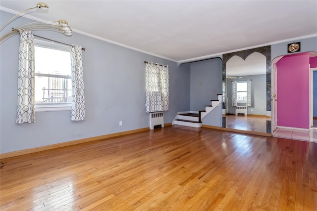 interior space with arched walkways, crown molding, wood-type flooring, and radiator