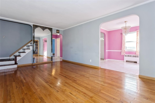 unfurnished living room with arched walkways, stairway, wood finished floors, and radiator